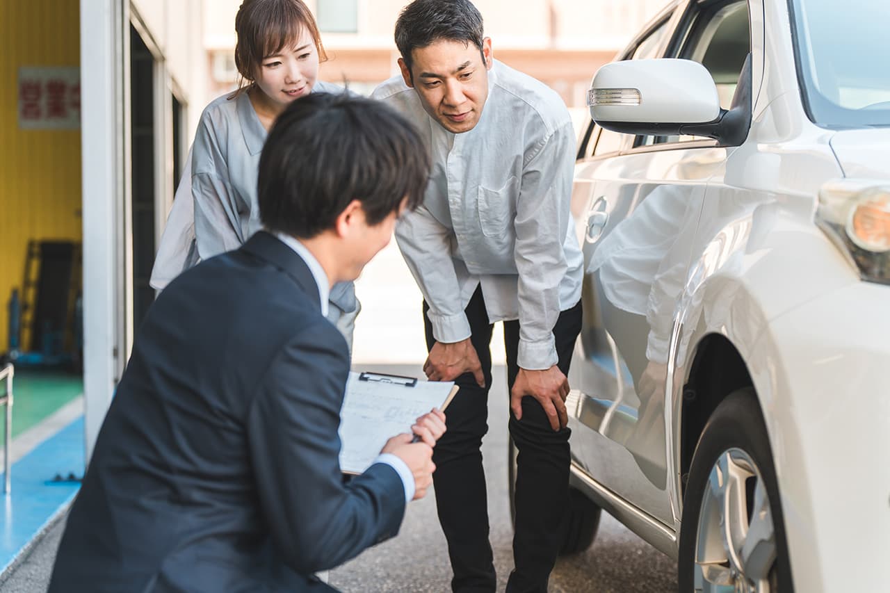 車の横で確認をしている営業マンとご夫婦