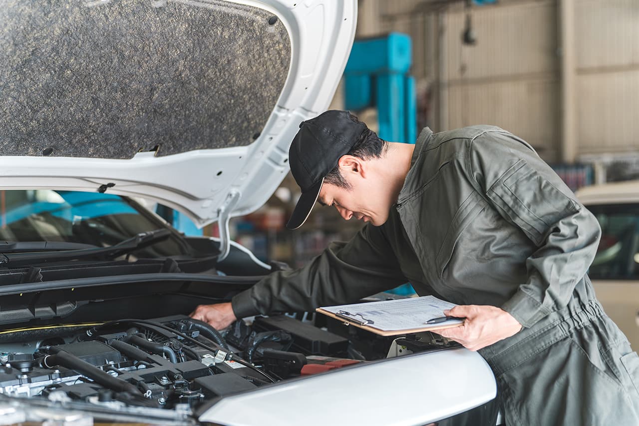 車のエンジンルームを点検する整備士