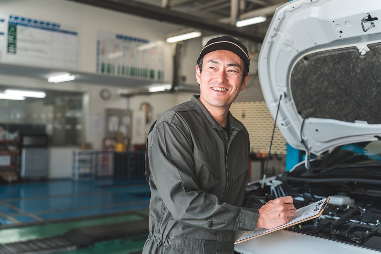車のフロントを確認している整備士
